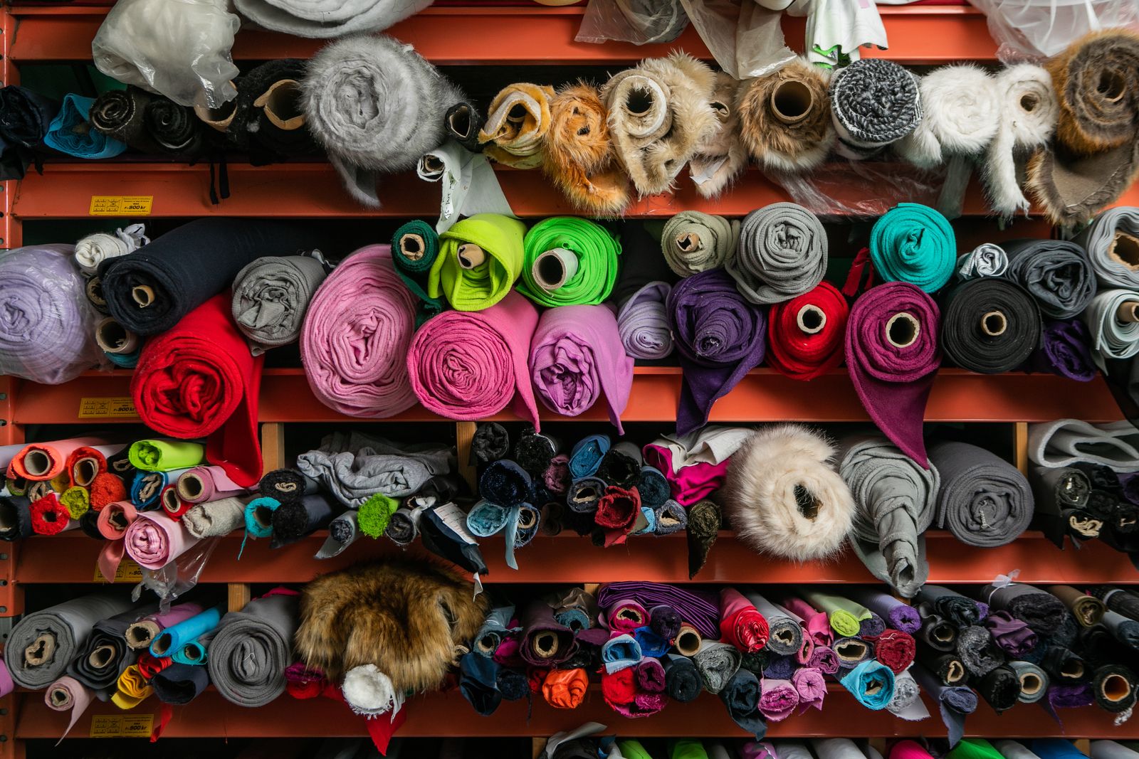 Rollos de tela de colores en los estantes de la bodega